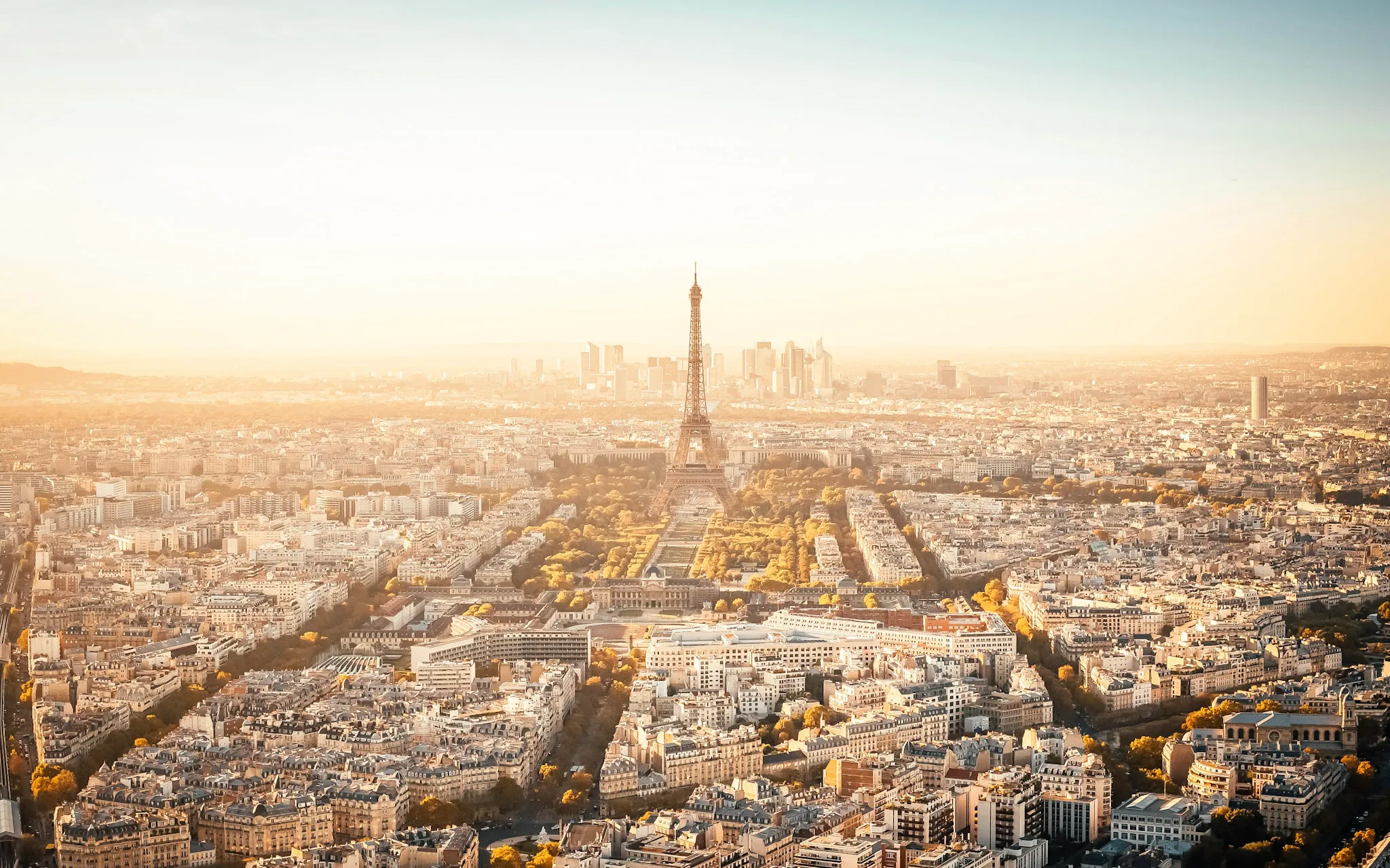 Voyages depuis Paris-CDG - Vue aérienne de Paris avec la Tour Eiffel et le quartier de La Défense au coucher de soleil